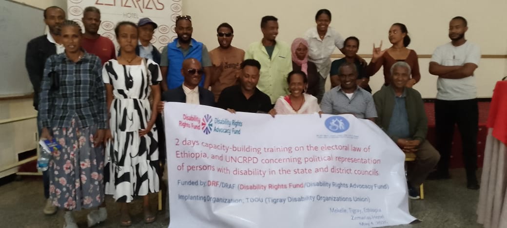 A group photo of men and women holding a banner at a disability rights capacity-building training session at Zemarias Hotel in Mekelle.